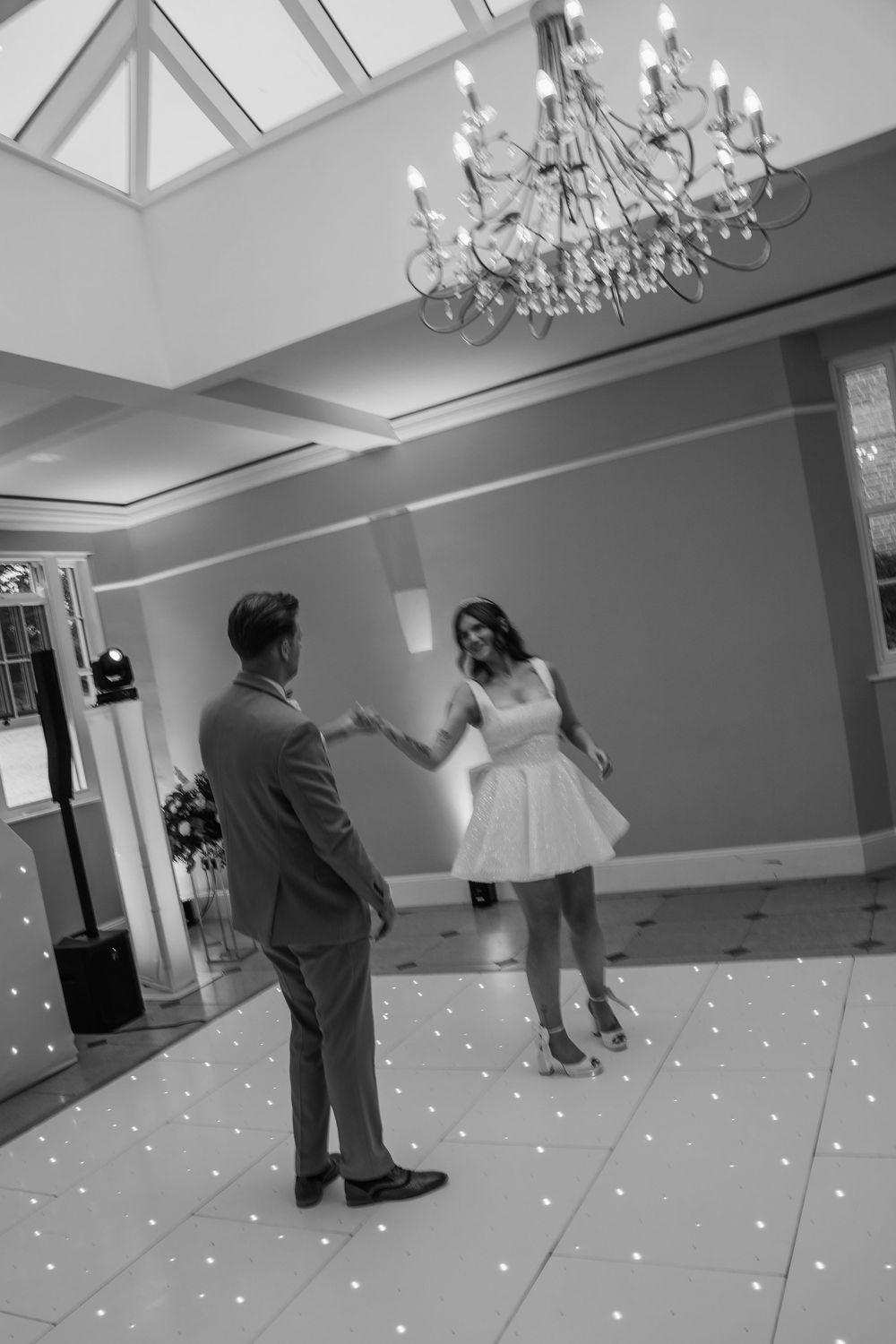 Newlyweds dancing at Rockbeare Manor reception under chandelier