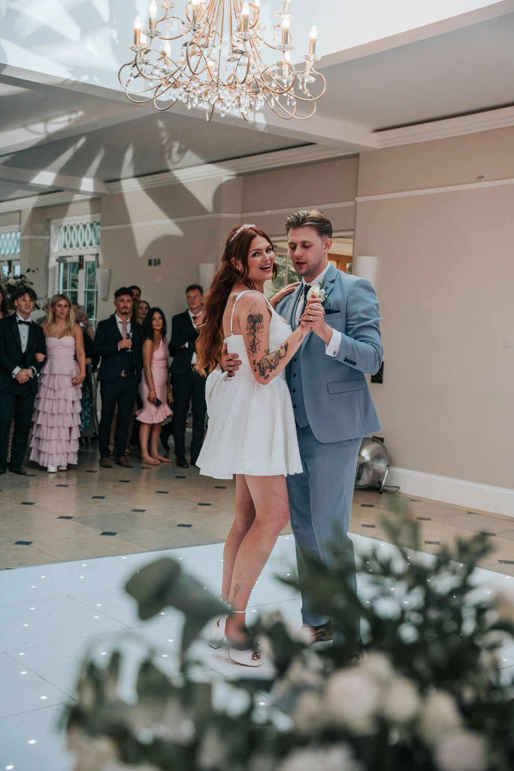 Newlyweds dancing at Rockbeare Manor reception under chandelier