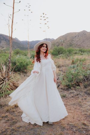 A dramatic white dress sweeps across desert terrain with mountains in the distance.