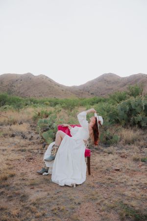 A white dress contrasts against the rugged desert landscape during a photo session.