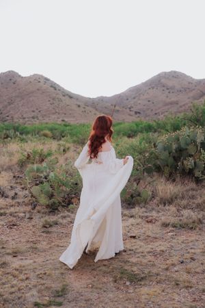 Flowing white fabric catches wind against desert mountain landscape.