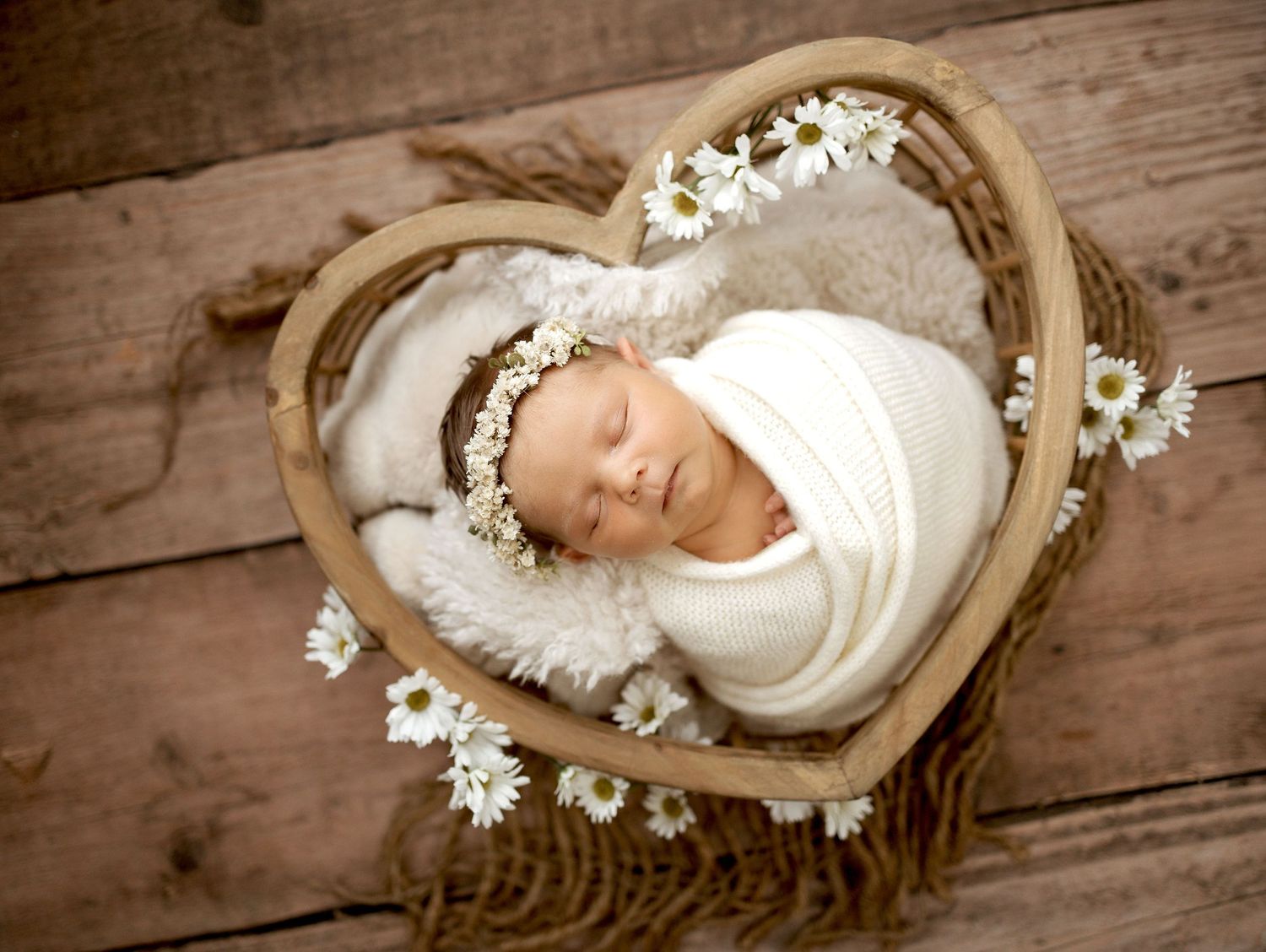Empty woven wicker basket in heart shape sits on rustic wooden table surface.
