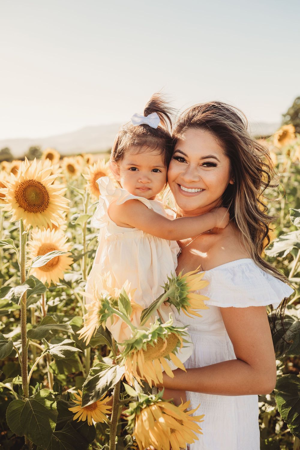 A heartwarming sunset portrait in a field of golden sunflowers shows a tender embrace amidst the blooming flowers.