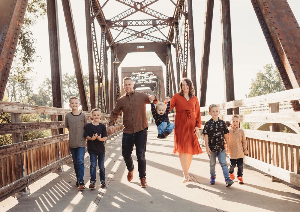 Several pedestrians walking across a long metal bridge structure in bright daylight.
