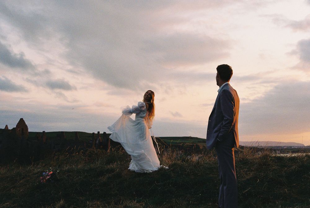 Couple eloping at Dunluce Castle in Northern Ireland running around the grass on film