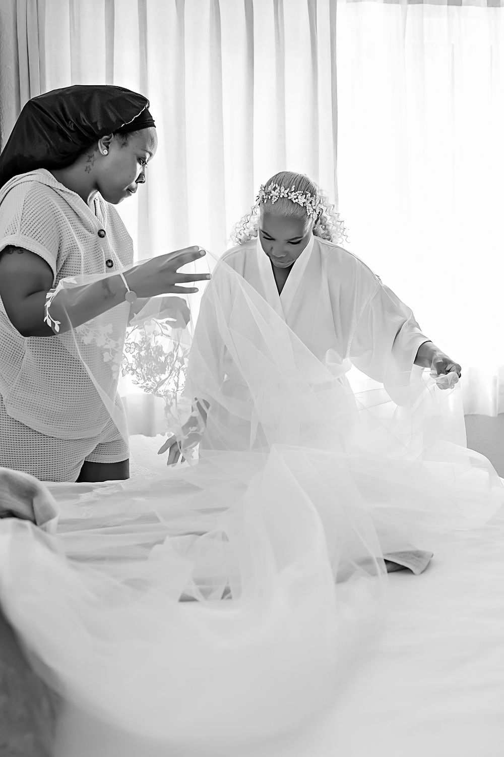 A soft, ethereal image of people working with flowing white fabric in a bright, light-filled room.