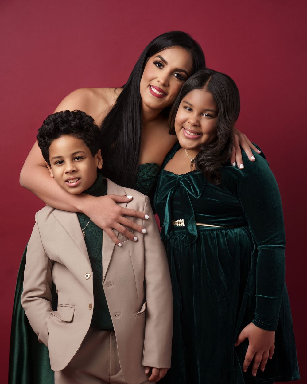 A portrait session with two figures in black and beige outfits against a burgundy backdrop showing warmth and connection.
