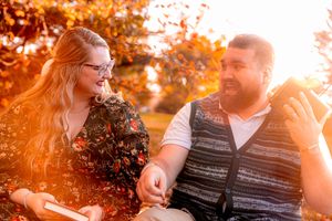 Golden sunset light illuminates a couple sharing a happy moment together in an autumn park setting.