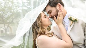 A romantic moment captured between newlyweds under a flowing veil in soft natural light.
