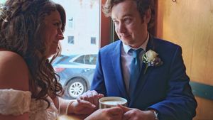 A bride and groom share an intimate moment together while sitting and holding hands at a restaurant table.