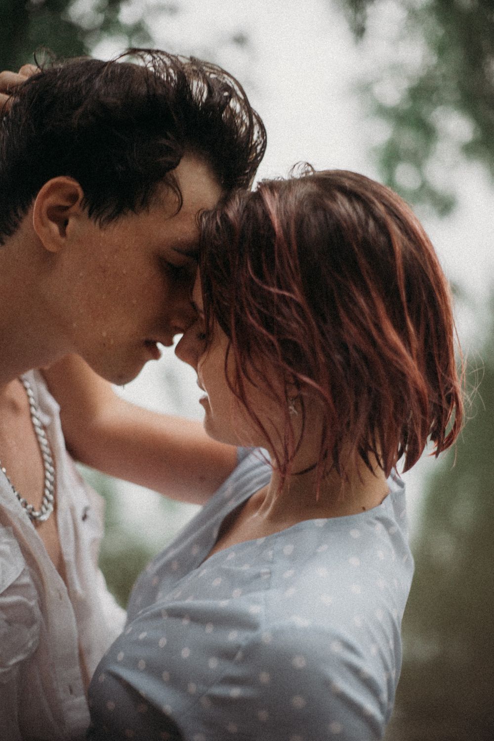 Romantic couple in white clothing sharing intimate moments in natural lighting.