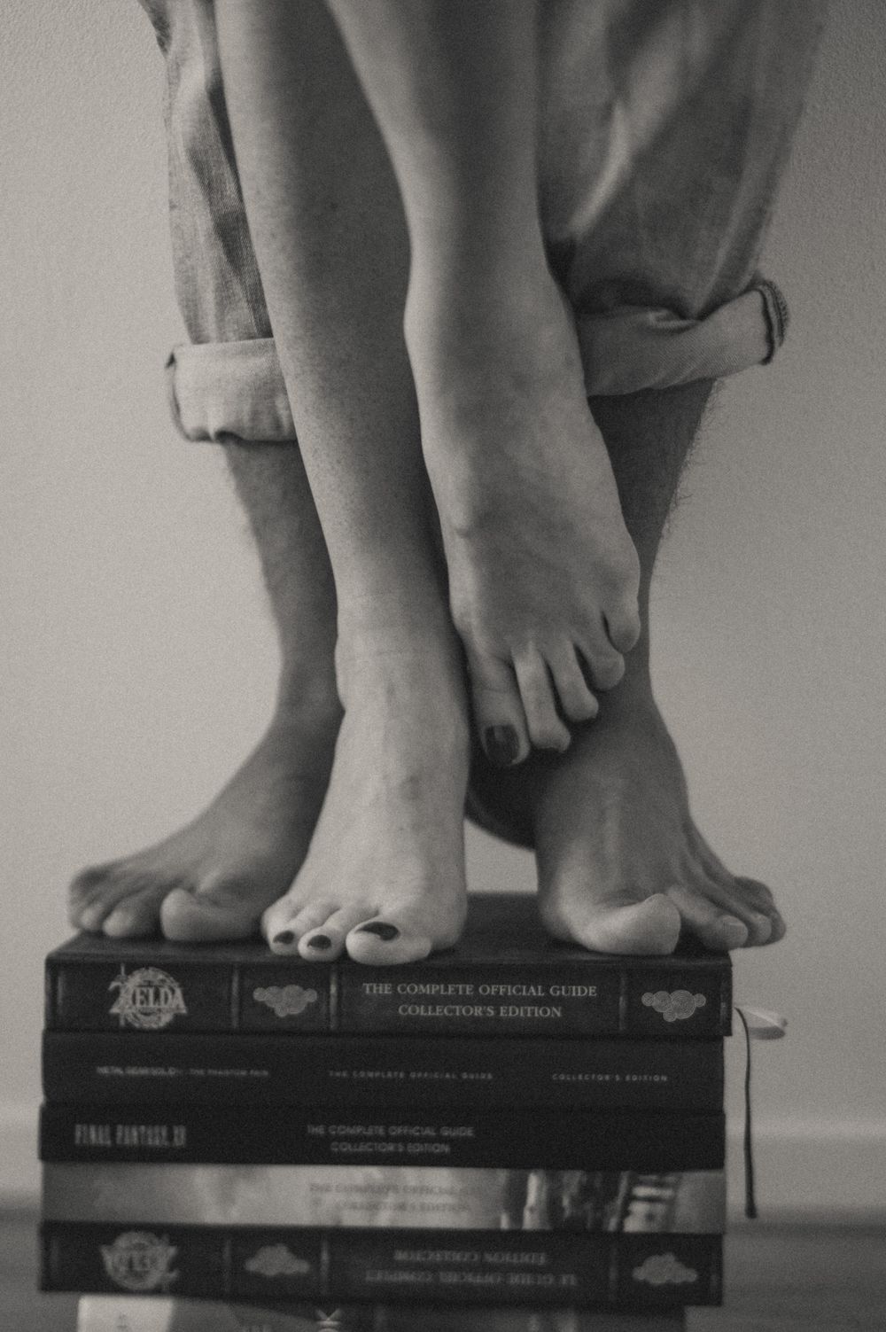 Artistic black and white photo of bare feet resting on stacked books.