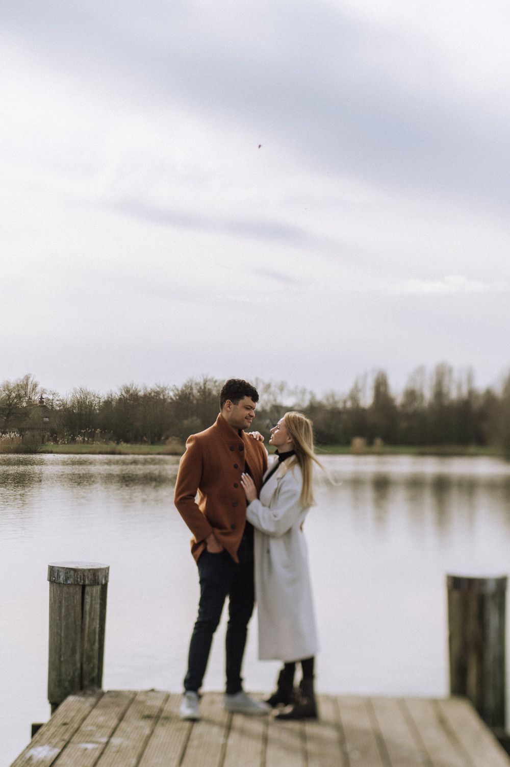 Romantic moment captured on a wooden dock overlooking a peaceful lake.