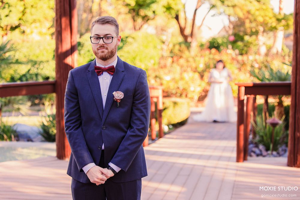 Groom in navy suit and groomsmen in matching attire pose together in an outdoor autumn setting.