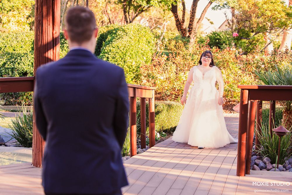 A first look wedding moment captured in a garden setting with warm autumn colors and wooden pergola details.