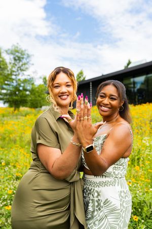 Two friends celebrate together in a sunny field of yellow wildflowers on a bright summer day.