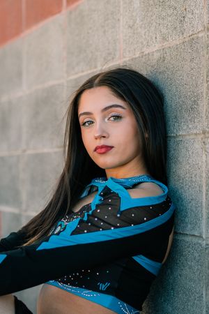 Dramatic urban portrait against concrete wall in blue and black performance wear.
