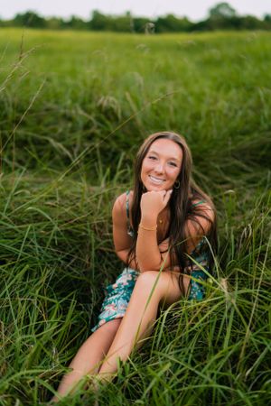 Joyful summer portrait in tall grass wearing a floral romper.