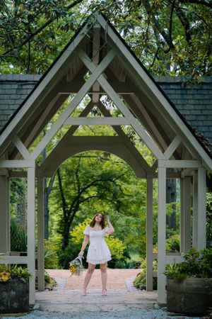 Enchanting scene under a white wooden gazebo surrounded by lush greenery.