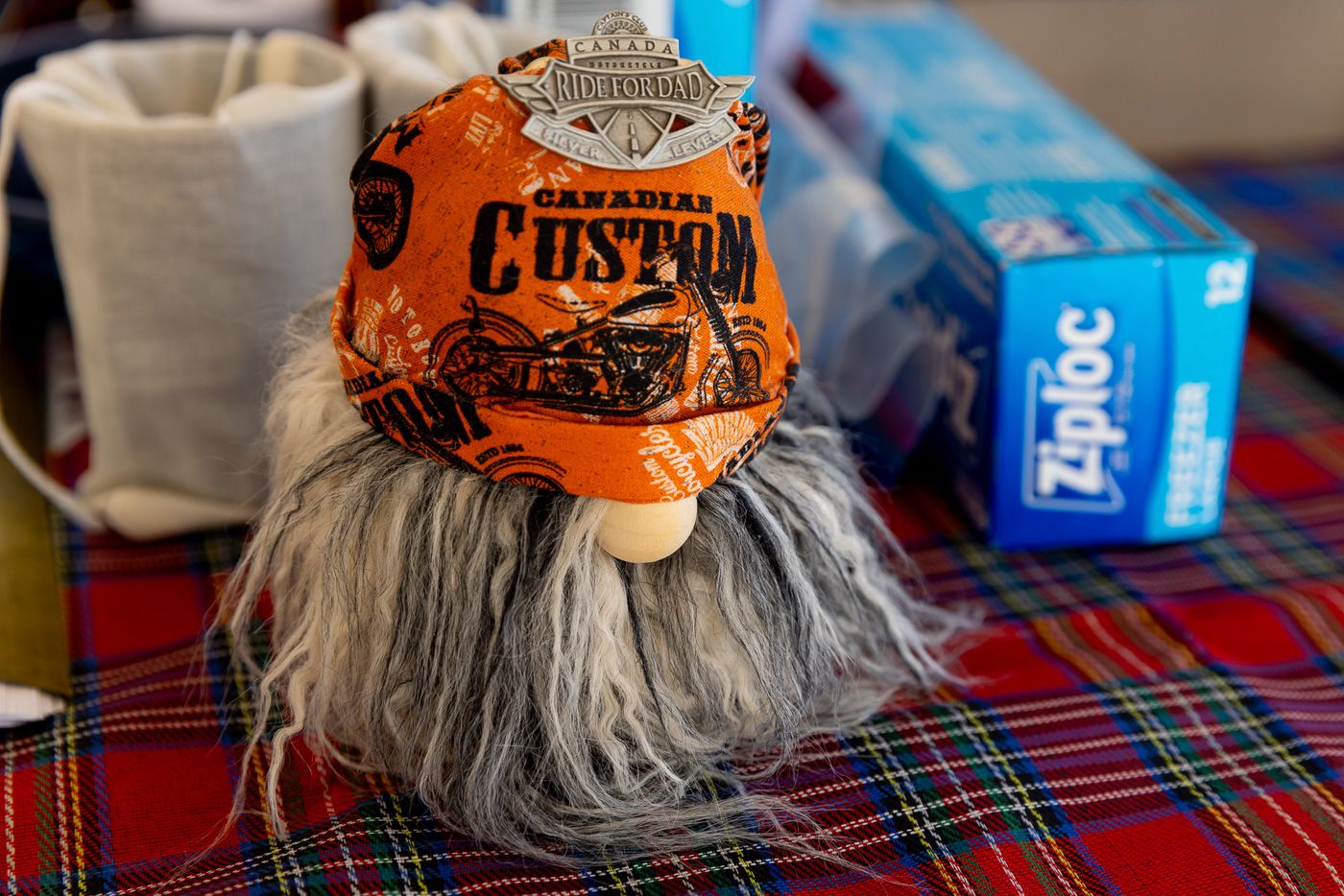 A fuzzy gnome decoration with long gray beard wears an orange Harley-Davidson Custom baseball cap.