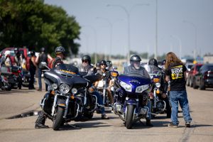 Group of motorcyclists gathered around their bikes at an outdoor event.