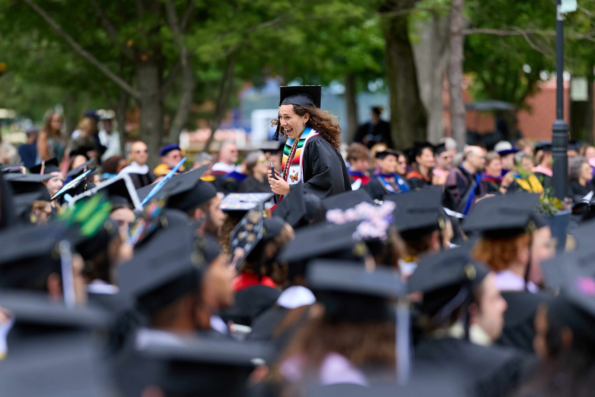 A graduate smiles as she runs through a crowd of students holding a diploma during a higher education commencement in Northeast Wisconsin.