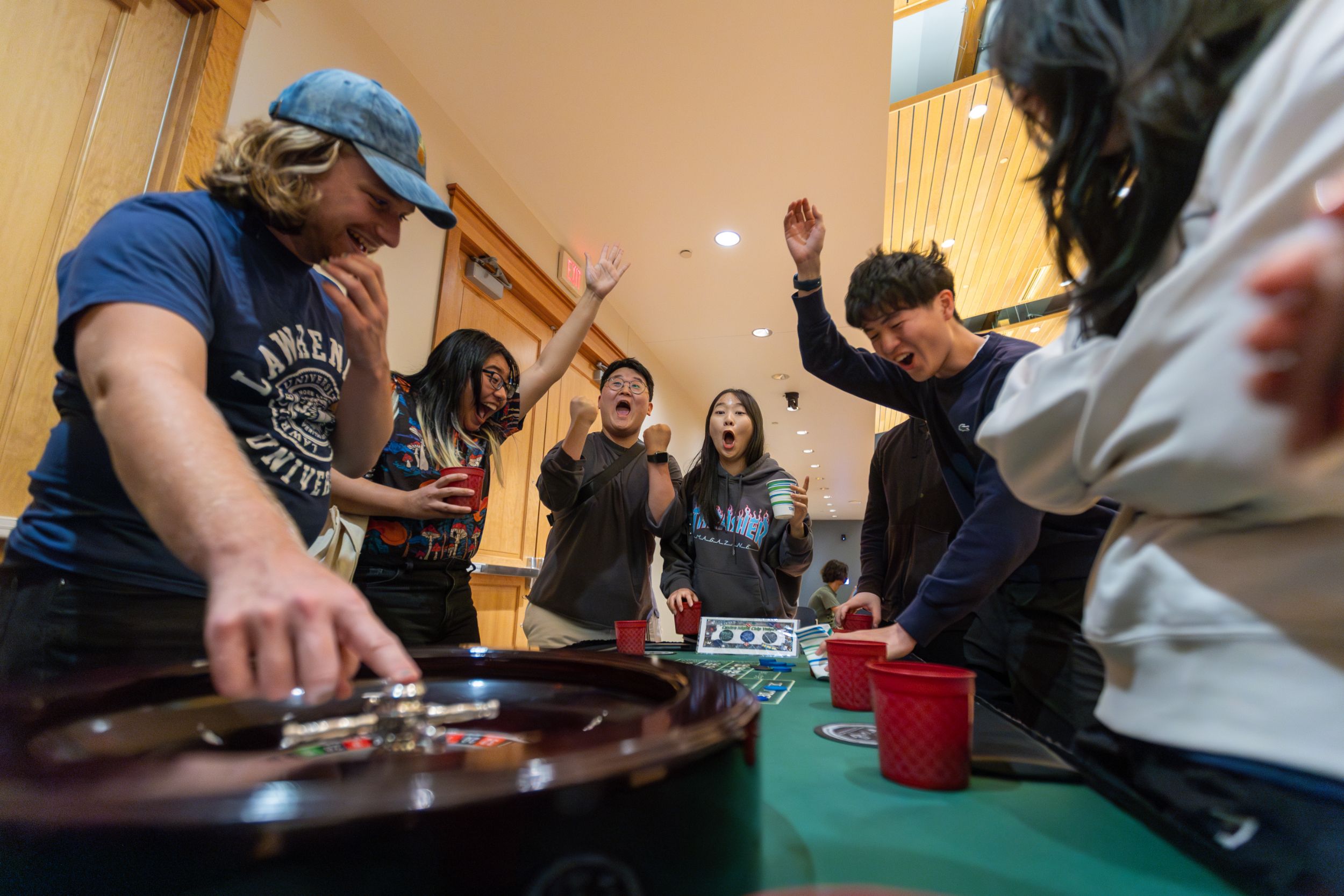Students celebrate around a roulette table during a casino night event.