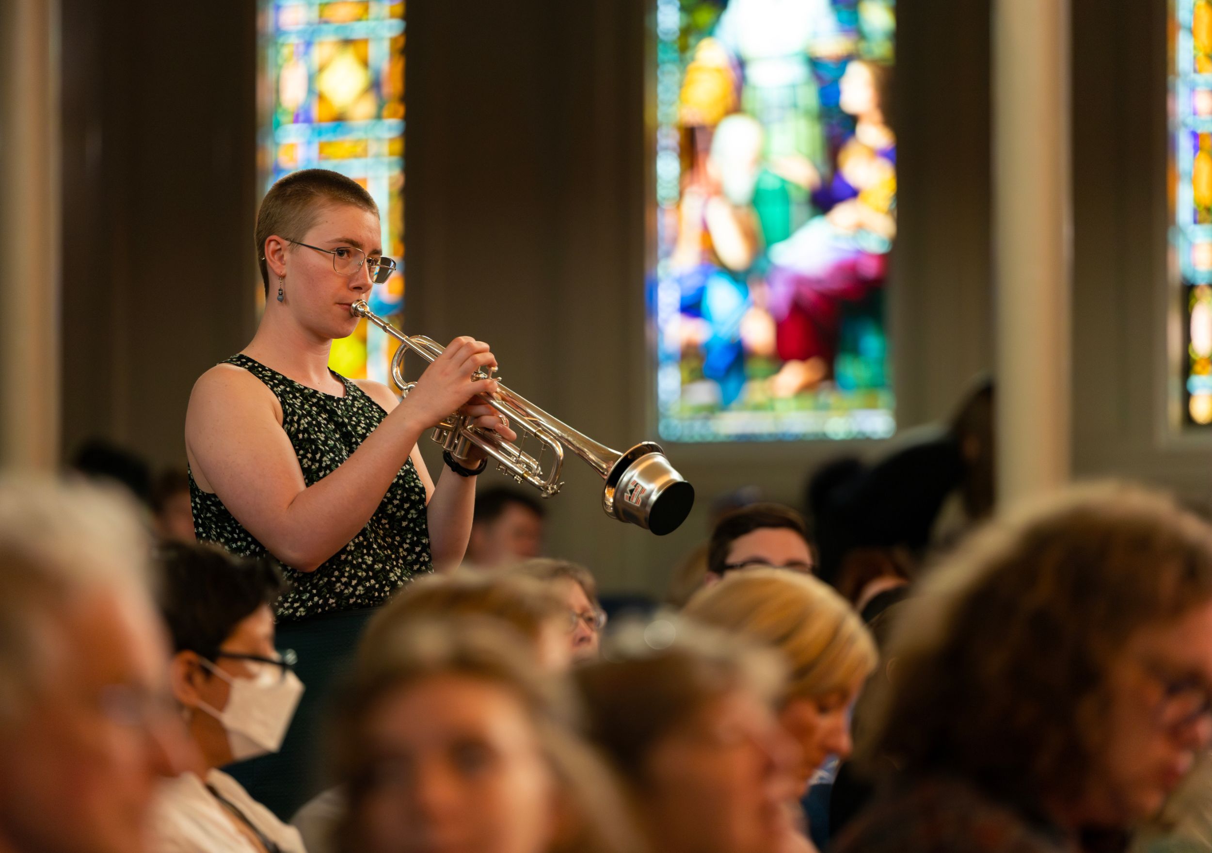 A trumpet players performs amongst a crowd.