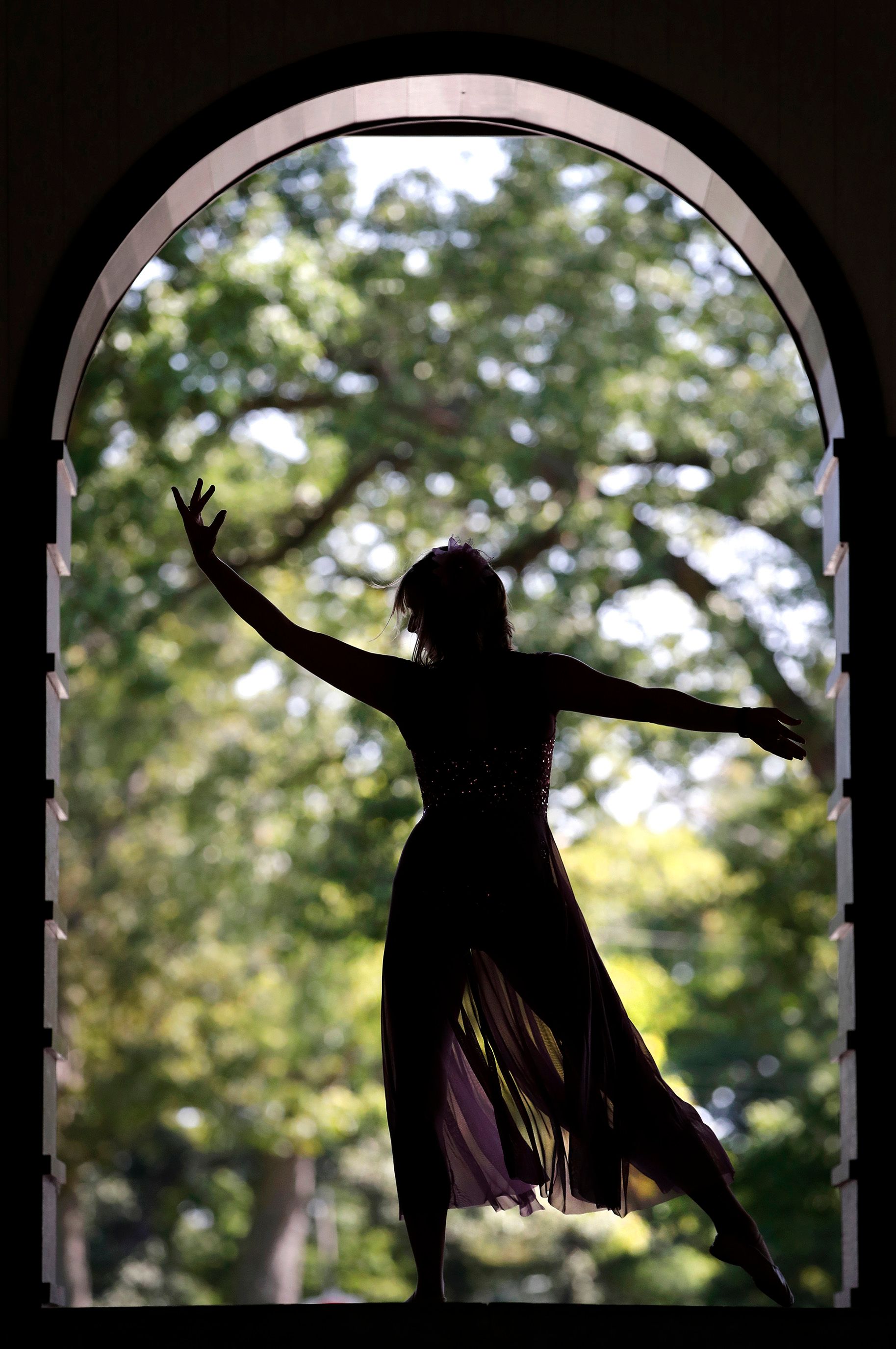 A dancer is silhouetted in an archway.