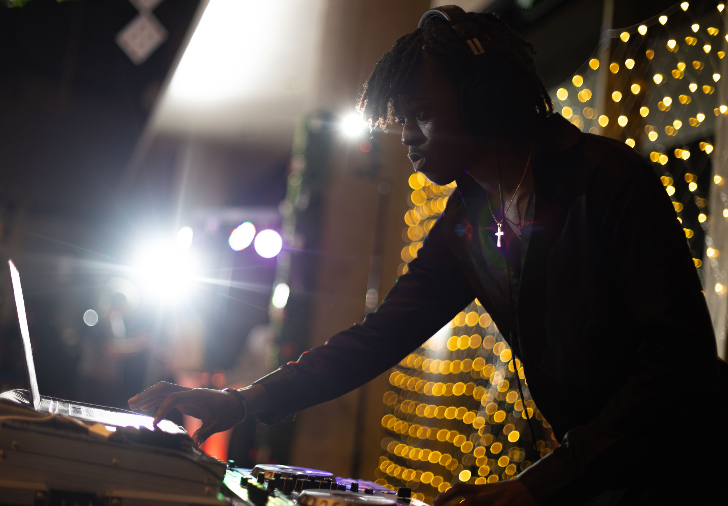 A DJ is silhouetted against lights.