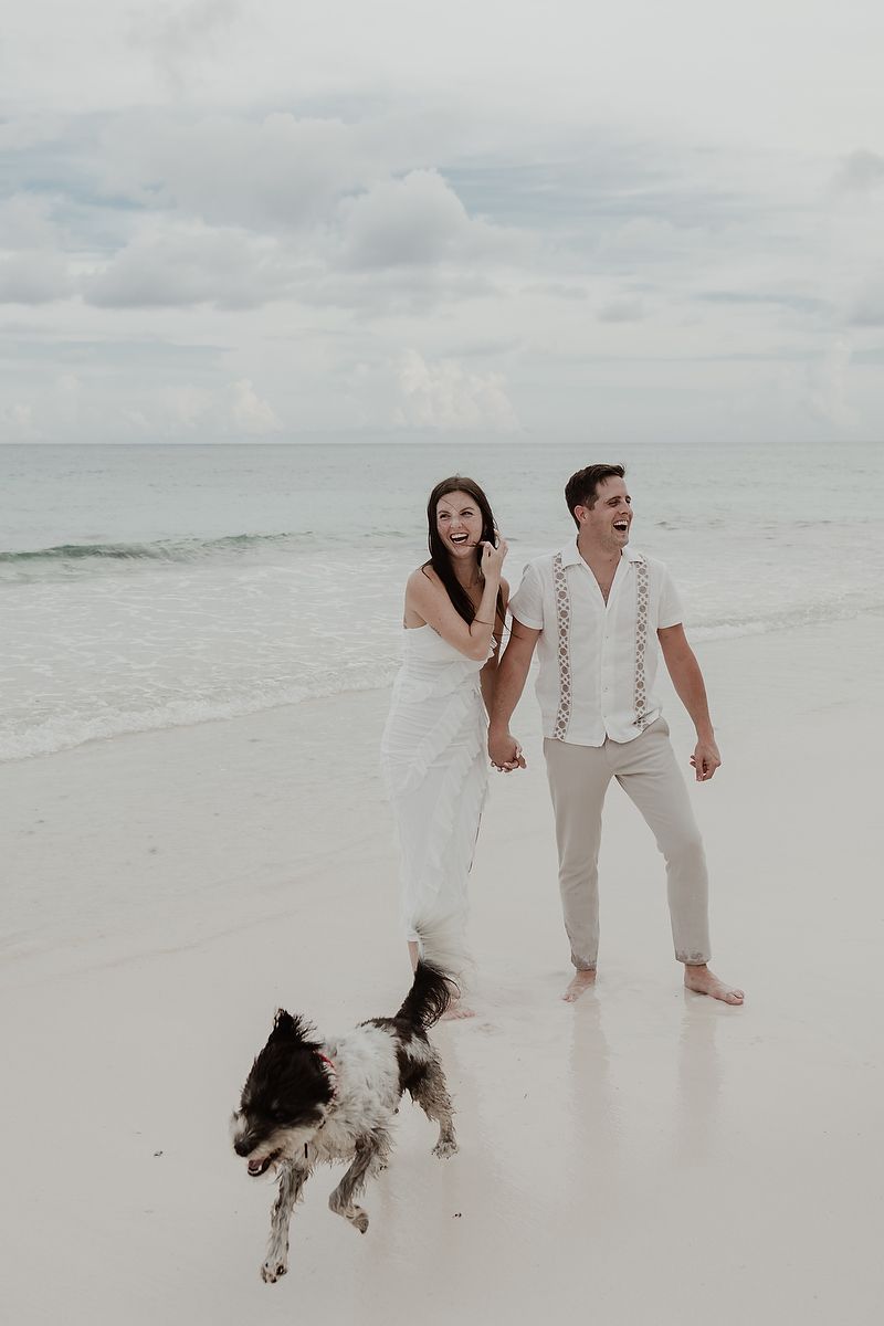 Couple walking with their dog on the beach during an engagement session in Mexico.