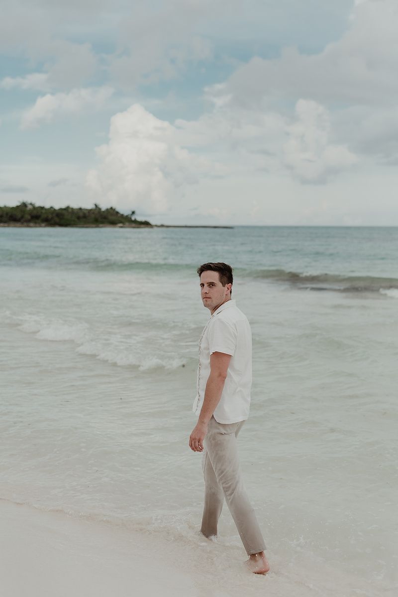 Stylish engagement portrait of a man walking on the shoreline at Playa Xpu Ha.