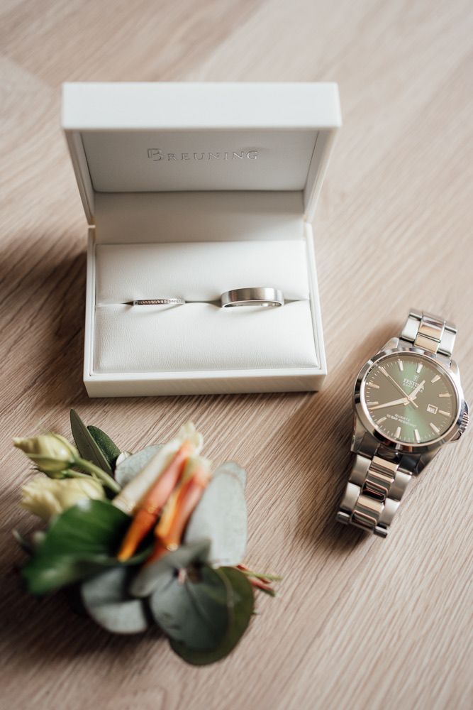 Elegant silver wristwatch displayed with delicate floral accents and white gift box on wooden surface.