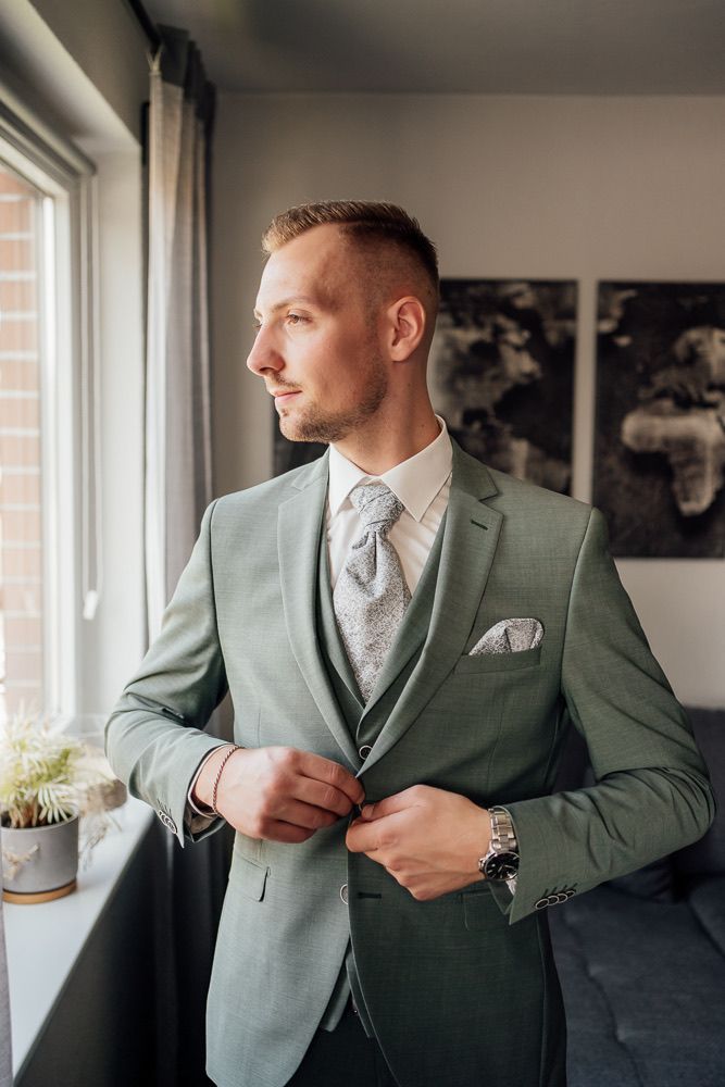 Side profile of someone wearing a mint green suit with matching pocket square in natural window light.