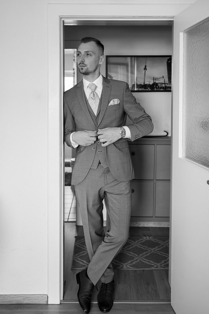 A sequence of black and white photos showing a person in a formal grey suit walking through a doorway.