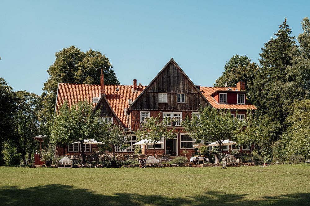 A panoramic view of rustic wooden houses and barns nestled among trees in a rural countryside setting.