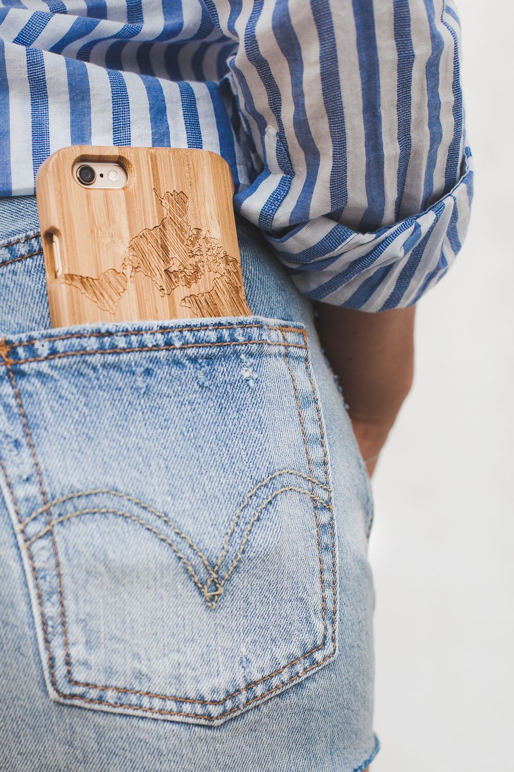 Bamboo wood engraved iPhone case peeking out of light wash Levis denim jeans back pocket.