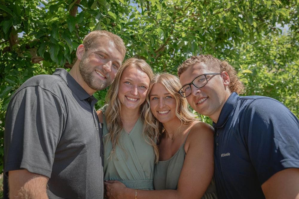 People gathered for a casual outdoor photo with lush greenery and natural lighting.