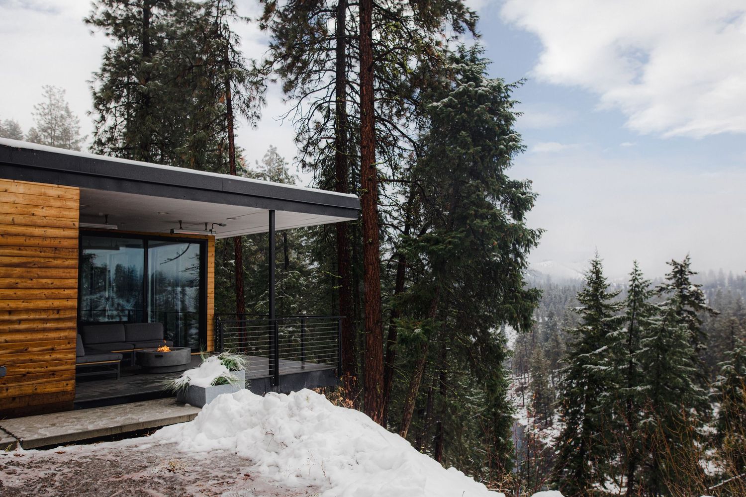 A modern cabin with glass walls sits nestled in a snowy landscape in Leavenworth Washington. A perfect place for an intimate elopement.