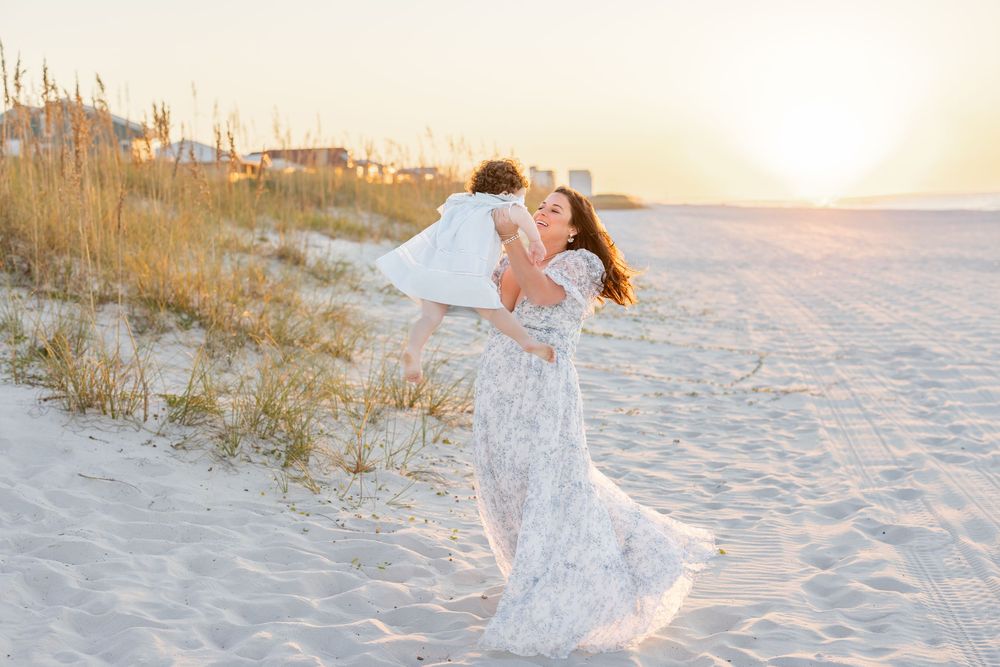 A romantic couple shares intimate moments on a white sandy beach at sunset in matching cream colored outfits.