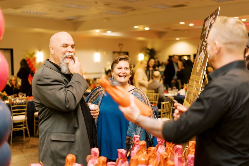 Wedding reception guests mingling and dancing in a warmly lit banquet hall.
