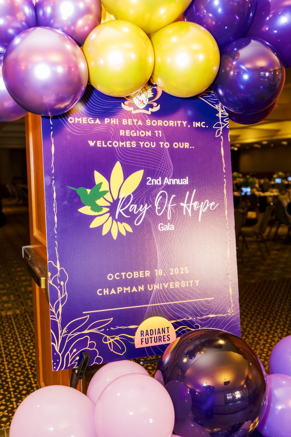 Purple and gold balloon decorations with event signage for 'Ray of Hope' at Chapman University.
