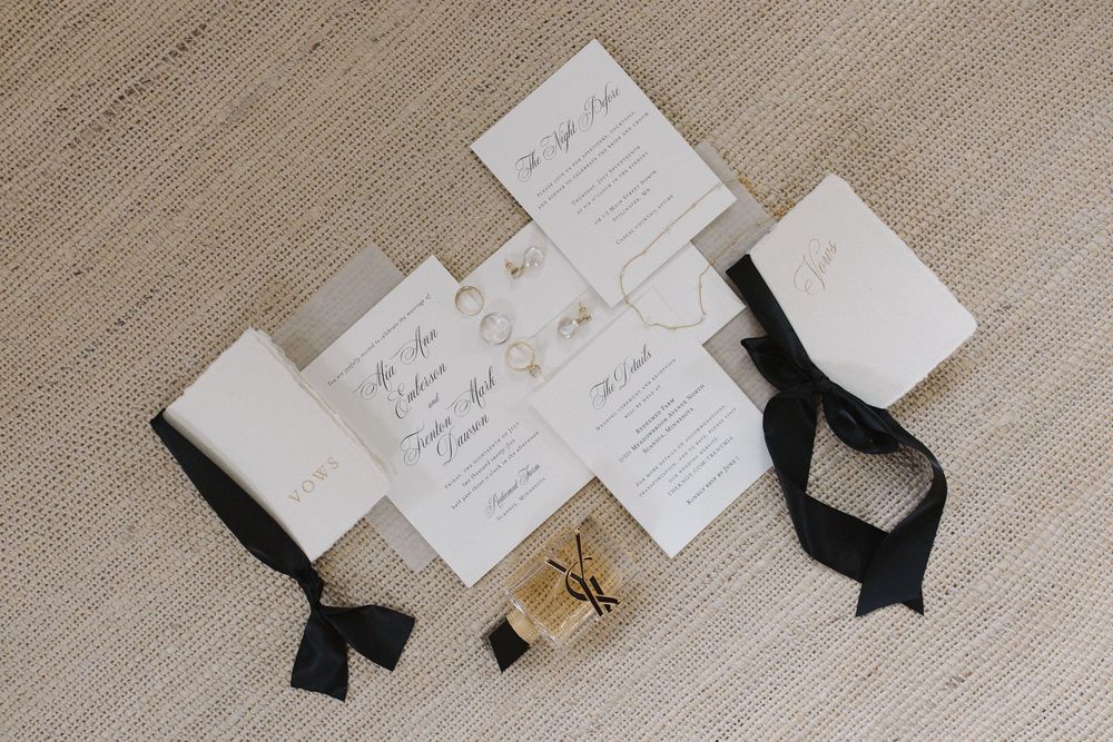 Collection of wedding stationery and paper goods arranged on textured fabric.