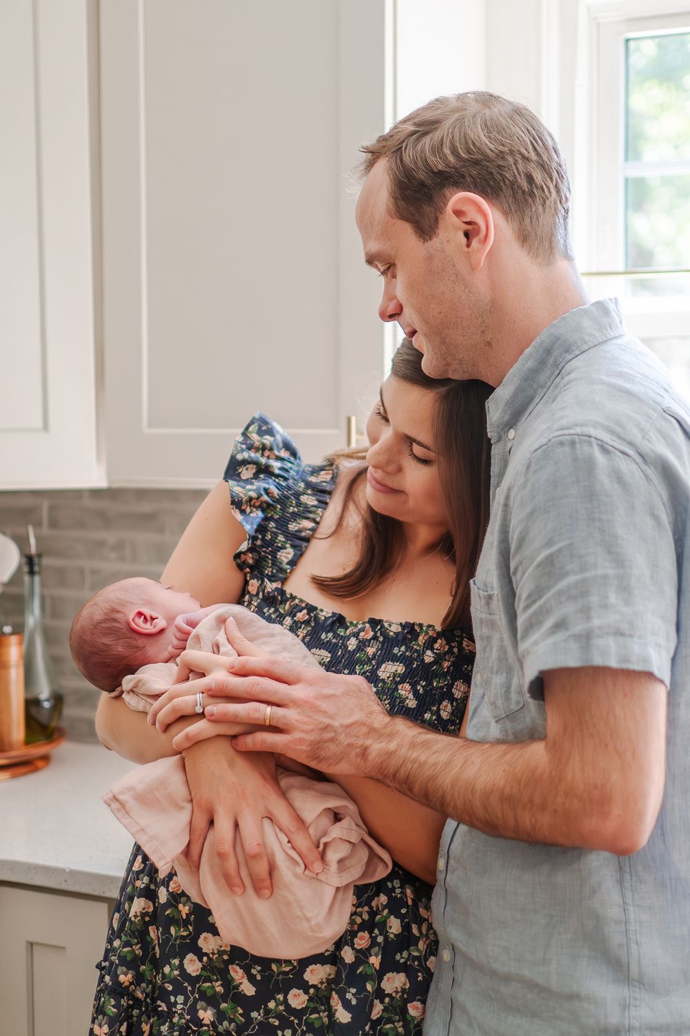 Happy couple sharing tender moments with their newborn baby in bright home setting.
