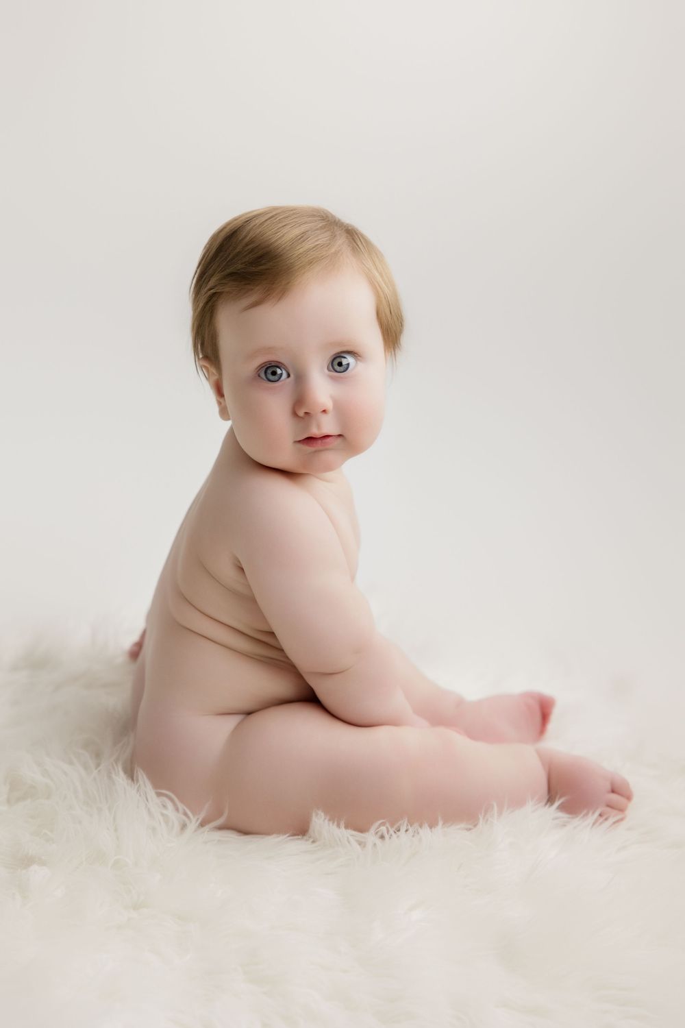 Series of baby milestone photos showing growth and development on white background with soft lighting.