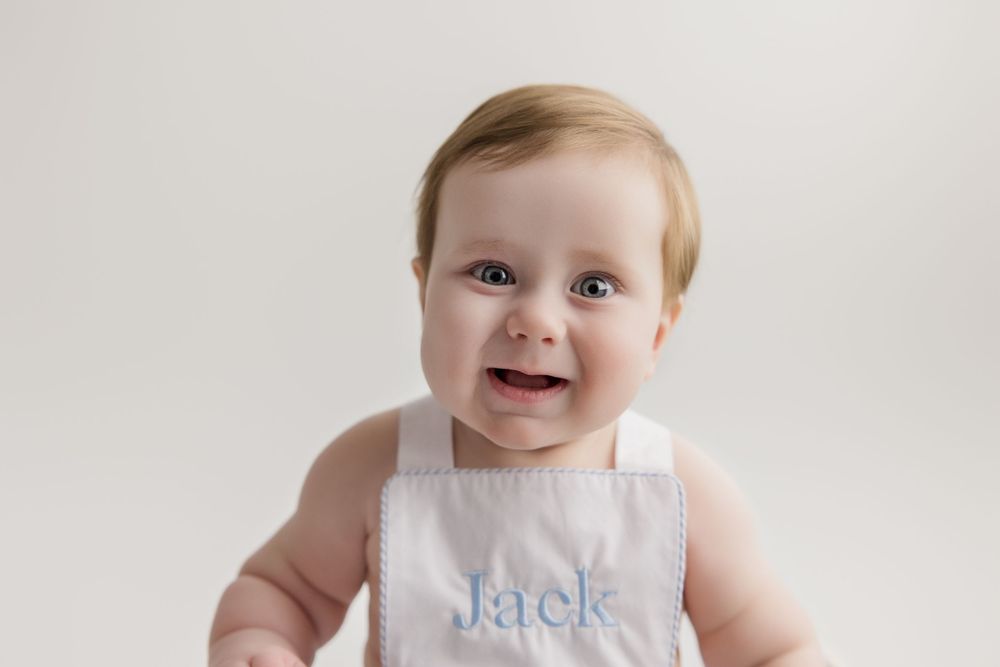 Four images showing a happy baby sitting on a white background wearing pink clothing and a bib.