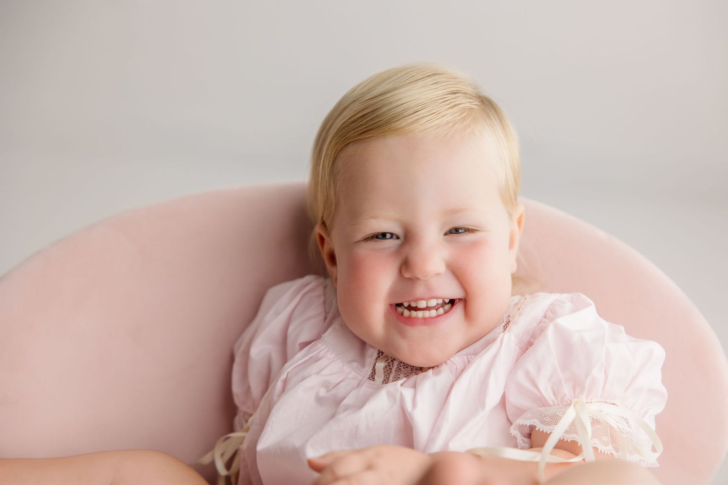 Sweet giggles and expressions are captured in a delicate pink and white portrait session.