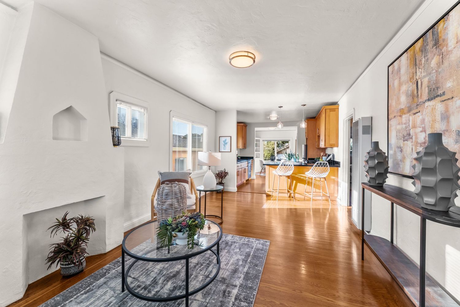 Modern open concept living room flows into kitchen with hardwood floors, sleek furniture, and contemporary decor.