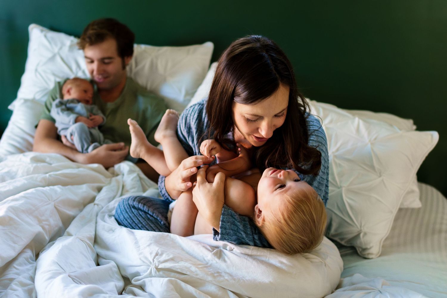 Family in bed with their newborn and toddler son during an in-home newborn session.