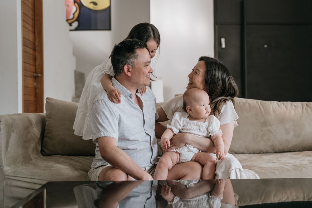 A family shares joyful moments together on a light-colored sofa.